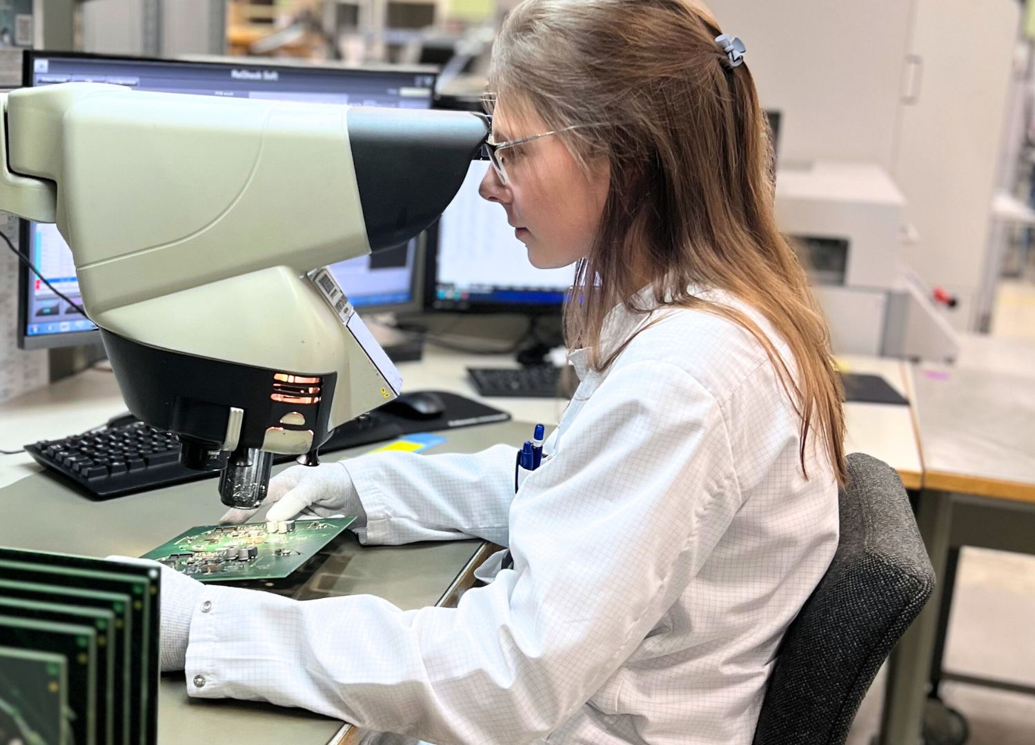 Inission Lohja electronics contract manufacturing – technician inspecting a circuit board to ensure high-quality production.